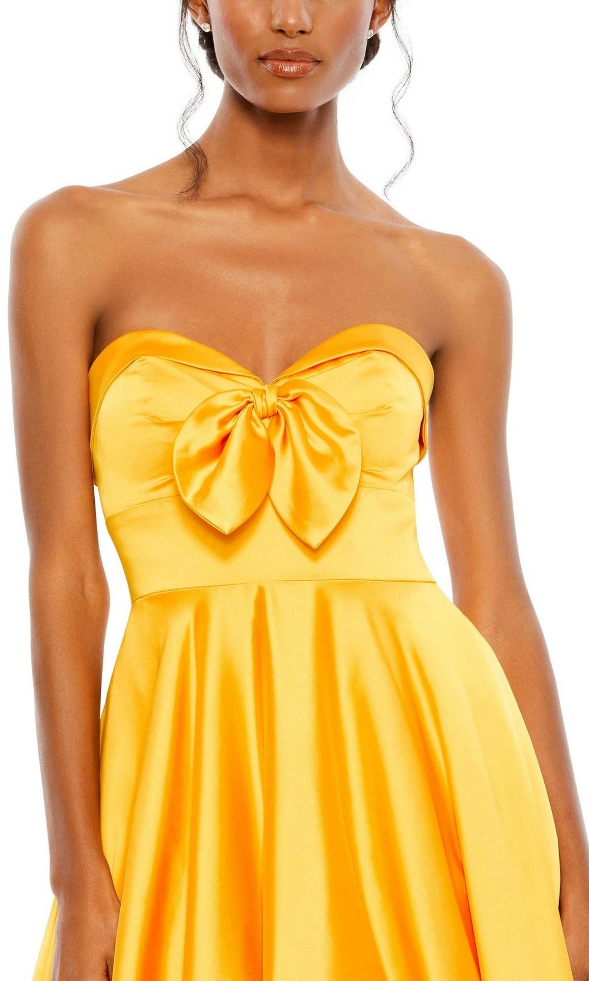 A woman wears the Long Formal Dress 67995 by Mac Duggal, a marigold yellow satin strapless ball gown with an A-line silhouette, sweetheart neckline, and a large bow detail at the chest.
